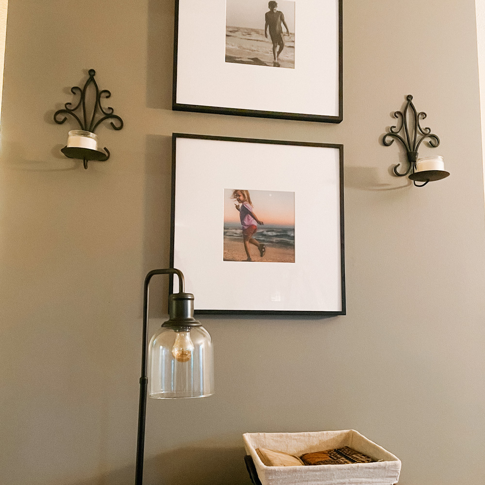 A wall with 2 square frames holding beach day photos