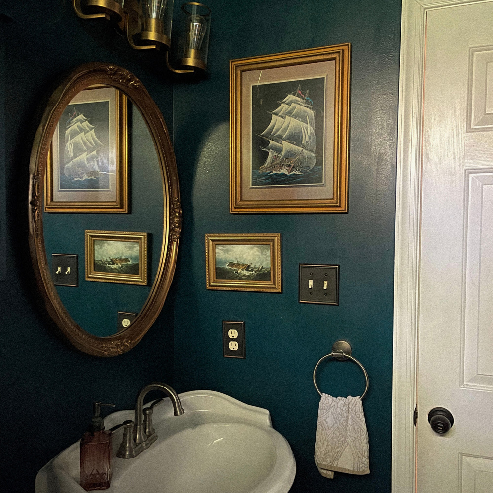 Bathroom Wall Decor Ideas: An Eccentric / Maximalist style bathroom with gold frames and dark blue walls.