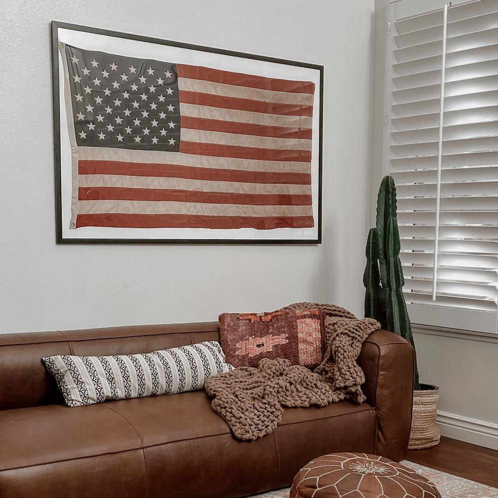 Custom Framing: A framed american flag hangs above a leather couch. 