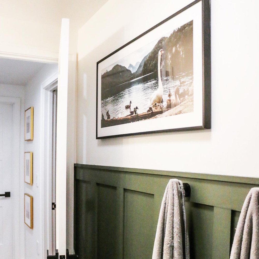 Bathroom Wall Decor Ideas: A Southern Chic bathroom with a framed photo of ducks in a pond above towels. 
